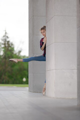 Girl ballerina in jeans, a plaid shirt and pointe shoes dancing in the city on the street © Tatiana