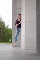 Girl ballerina in jeans, a plaid shirt and pointe shoes dancing in the city on the street © Tatiana