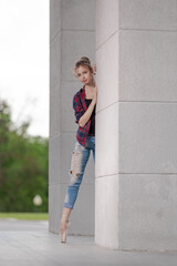 Girl ballerina in jeans, a plaid shirt and pointe shoes dancing in the city on the street © Tatiana
