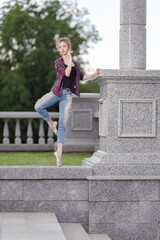 Girl ballerina in jeans, a plaid shirt and pointe shoes dancing in the city on the street © Tatiana