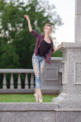 Girl ballerina in jeans, a plaid shirt and pointe shoes dancing in the city on the street © Tatiana