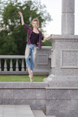 Girl ballerina in jeans, a plaid shirt and pointe shoes dancing in the city on the street © Tatiana