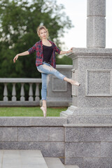 Girl ballerina in jeans, a plaid shirt and pointe shoes dancing in the city on the street © Tatiana