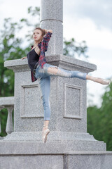Girl ballerina in jeans, a plaid shirt and pointe shoes dancing in the city on the street © Tatiana
