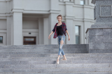 Girl ballerina in jeans, a plaid shirt and pointe shoes dancing in the city on the street © Tatiana