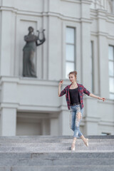 Girl ballerina in jeans, a plaid shirt and pointe shoes dancing in the city on the street © Tatiana