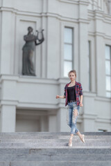 Girl ballerina in jeans, a plaid shirt and pointe shoes dancing in the city on the street © Tatiana