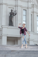 Girl ballerina in jeans, a plaid shirt and pointe shoes dancing in the city on the street © Tatiana