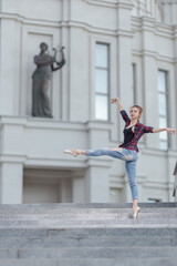 Girl ballerina in jeans, a plaid shirt and pointe shoes dancing in the city on the street © Tatiana