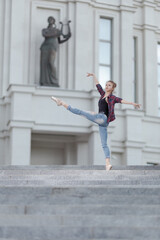 Girl ballerina in jeans, a plaid shirt and pointe shoes dancing in the city on the street © Tatiana