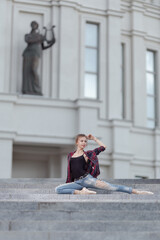 Girl ballerina in jeans, a plaid shirt and pointe shoes dancing in the city on the street © Tatiana