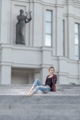 Girl ballerina in jeans, a plaid shirt and pointe shoes dancing in the city on the street © Tatiana
