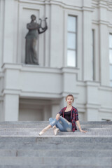 Girl ballerina in jeans, a plaid shirt and pointe shoes dancing in the city on the street © Tatiana
