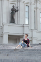 Girl ballerina in jeans, a plaid shirt and pointe shoes dancing in the city on the street © Tatiana