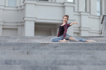 Girl ballerina in jeans, a plaid shirt and pointe shoes dancing in the city on the street © Tatiana