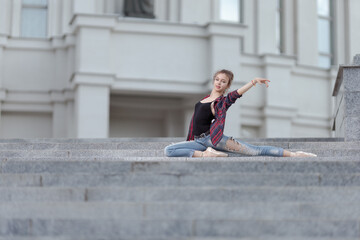 Girl ballerina in jeans, a plaid shirt and pointe shoes dancing in the city on the street © Tatiana