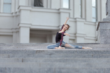 Girl ballerina in jeans, a plaid shirt and pointe shoes dancing in the city on the street © Tatiana
