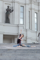 Girl ballerina in jeans, a plaid shirt and pointe shoes dancing in the city on the street © Tatiana