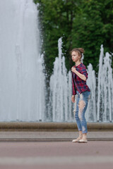 Girl ballerina in jeans, a plaid shirt and pointe shoes dancing in the city on the street © Tatiana