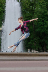Girl ballerina in jeans, a plaid shirt and pointe shoes dancing in the city on the street © Tatiana