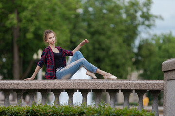Girl ballerina in jeans, a plaid shirt and pointe shoes dancing in the city on the street © Tatiana