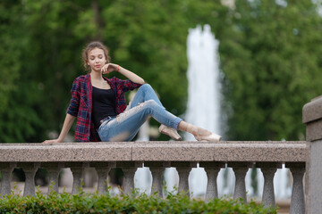 Girl ballerina in jeans, a plaid shirt and pointe shoes dancing in the city on the street © Tatiana