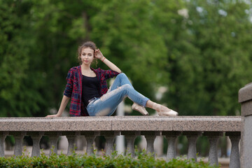 Girl ballerina in jeans, a plaid shirt and pointe shoes dancing in the city on the street © Tatiana