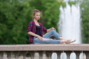 Girl ballerina in jeans, a plaid shirt and pointe shoes dancing in the city on the street © Tatiana