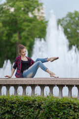Girl ballerina in jeans, a plaid shirt and pointe shoes dancing in the city on the street © Tatiana
