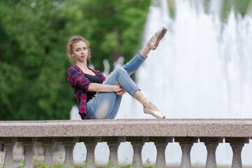 Girl ballerina in jeans, a plaid shirt and pointe shoes dancing in the city on the street © Tatiana