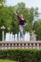 Girl ballerina in jeans, a plaid shirt and pointe shoes dancing in the city on the street © Tatiana