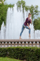 Girl ballerina in jeans, a plaid shirt and pointe shoes dancing in the city on the street © Tatiana