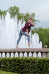 Girl ballerina in jeans, a plaid shirt and pointe shoes dancing in the city on the street © Tatiana
