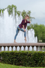 Girl ballerina in jeans, a plaid shirt and pointe shoes dancing in the city on the street © Tatiana