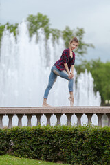 Girl ballerina in jeans, a plaid shirt and pointe shoes dancing in the city on the street © Tatiana