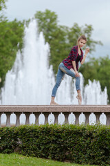 Girl ballerina in jeans, a plaid shirt and pointe shoes dancing in the city on the street © Tatiana