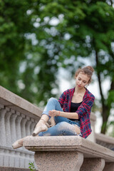 Girl ballerina in jeans, a plaid shirt and pointe shoes dancing in the city on the street © Tatiana