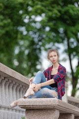 Girl ballerina in jeans, a plaid shirt and pointe shoes dancing in the city on the street © Tatiana