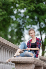 Girl ballerina in jeans, a plaid shirt and pointe shoes dancing in the city on the street © Tatiana