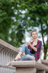 Girl ballerina in jeans, a plaid shirt and pointe shoes dancing in the city on the street © Tatiana