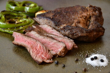 Close up Sliced medium rare grilled steak with salt,Bell pepper and rosemary placed on plate.