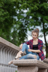 Girl ballerina in jeans, a plaid shirt and pointe shoes dancing in the city on the street © Tatiana