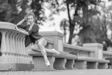 Black and white photo of a ballerina girl in jeans and pointe shoes, dancing and posing in the city on the street © Tatiana
