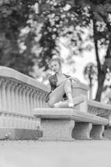 Black and white photo of a ballerina girl in jeans and pointe shoes, dancing and posing in the city on the street © Tatiana