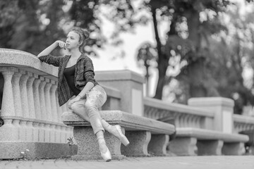 Black and white photo of a ballerina girl in jeans and pointe shoes, dancing and posing in the city on the street © Tatiana