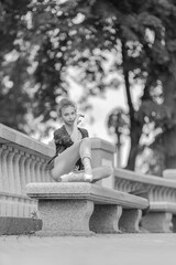 Black and white photo of a ballerina girl in jeans and pointe shoes, dancing and posing in the city on the street © Tatiana