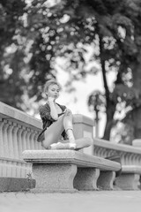 Black and white photo of a ballerina girl in jeans and pointe shoes, dancing and posing in the city on the street © Tatiana