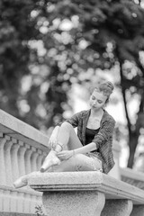 Black and white photo of a ballerina girl in jeans and pointe shoes, dancing and posing in the city on the street © Tatiana
