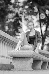 Black and white photo of a ballerina girl in jeans and pointe shoes, dancing and posing in the city on the street © Tatiana
