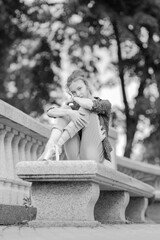 Black and white photo of a ballerina girl in jeans and pointe shoes, dancing and posing in the city on the street © Tatiana